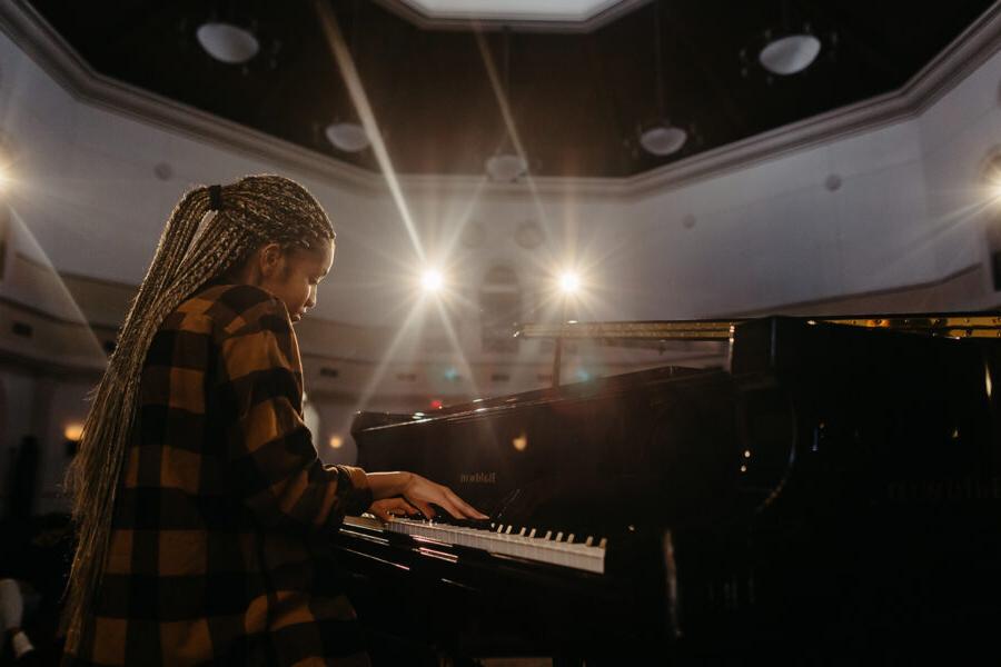 Music student plays the piano in an auditorium.